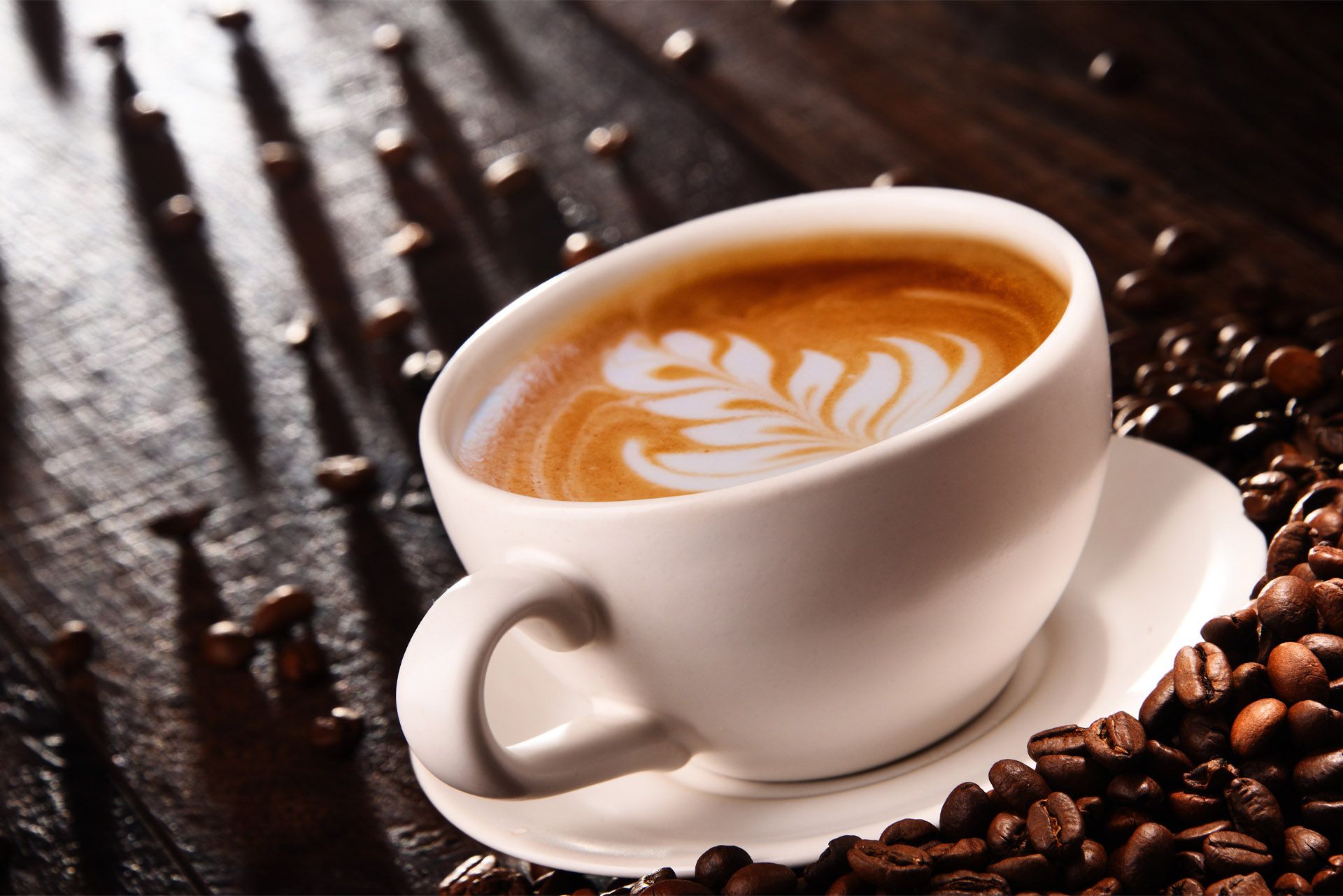 Cappuccino con latte art accanto a chicchi di caffè